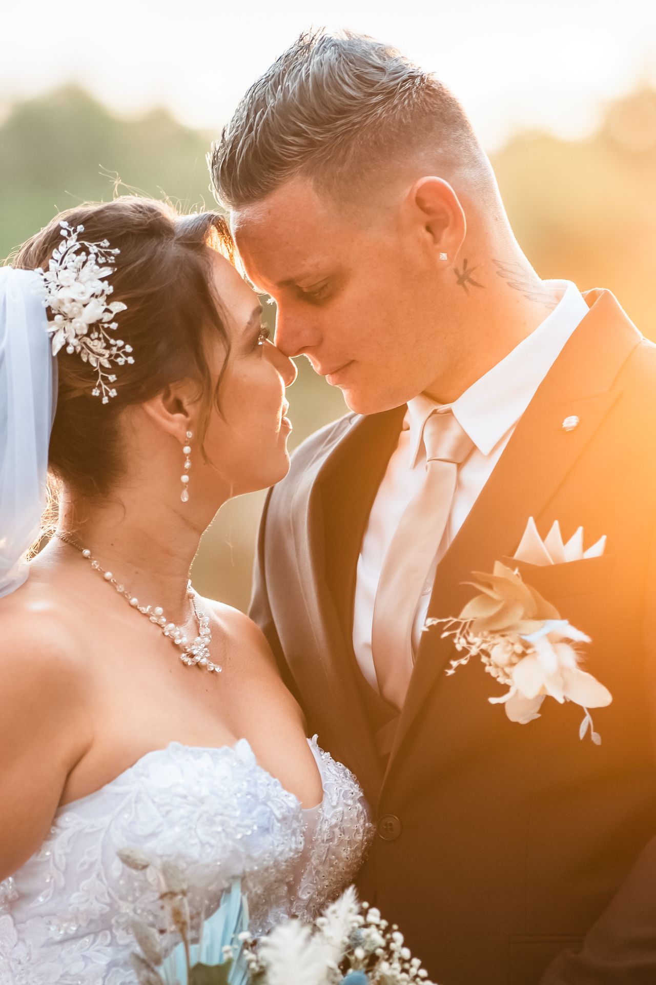 Romantic wedding moment captured in warm golden light with bride in lace gown and groom in elegant suit.