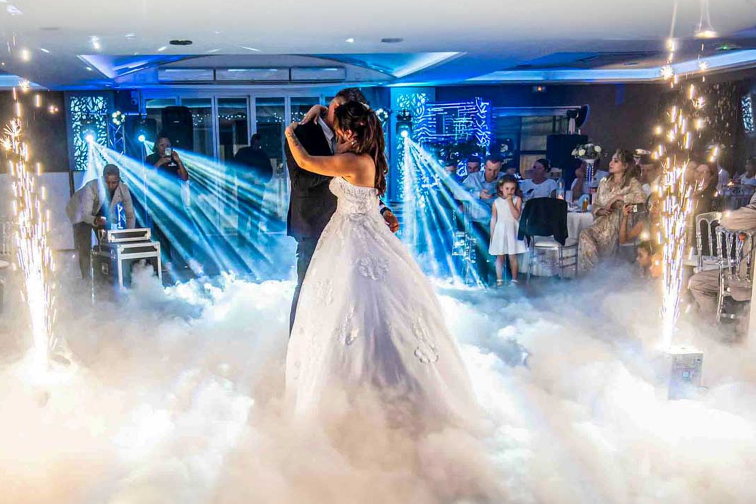 A dreamy first dance at a wedding reception with dramatic blue lighting, fog effects and sparkling lights in the background.