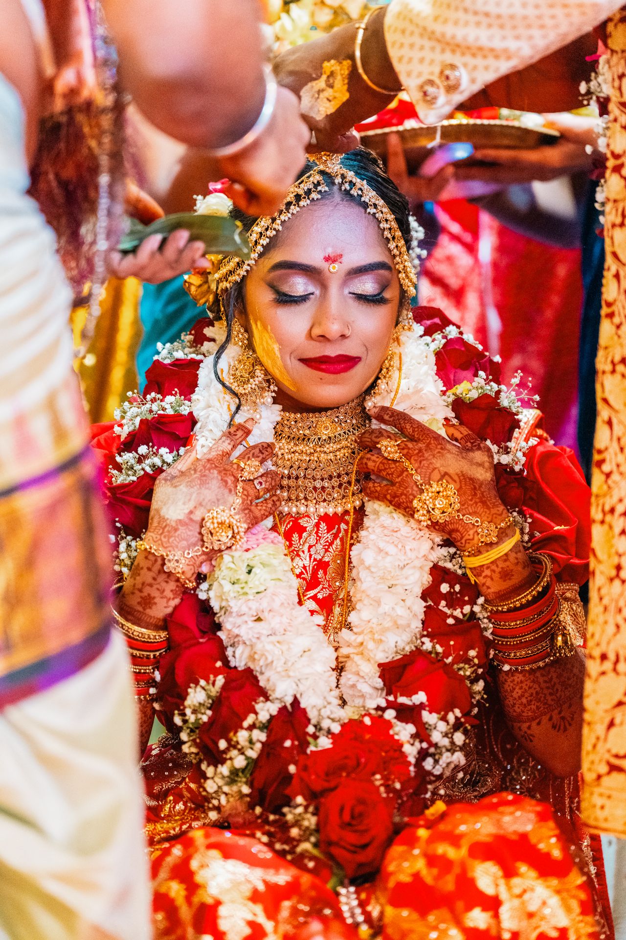 Traditional Indian wedding ceremony with ornate bridal jewelry, floral garlands and red attire.