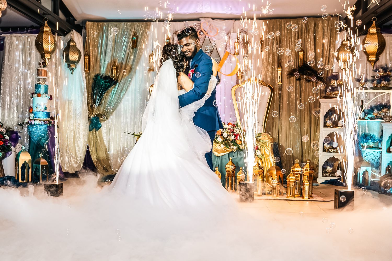 A couple sharing their first dance on a misty dance floor with elegant decor and chandelier lighting.