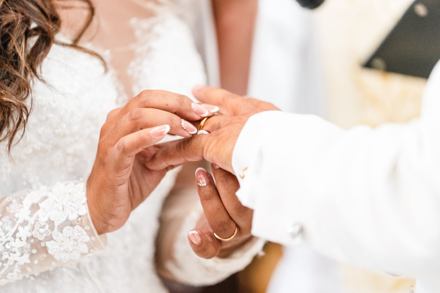 Close up view of hands exchanging wedding rings during a wedding ceremony.