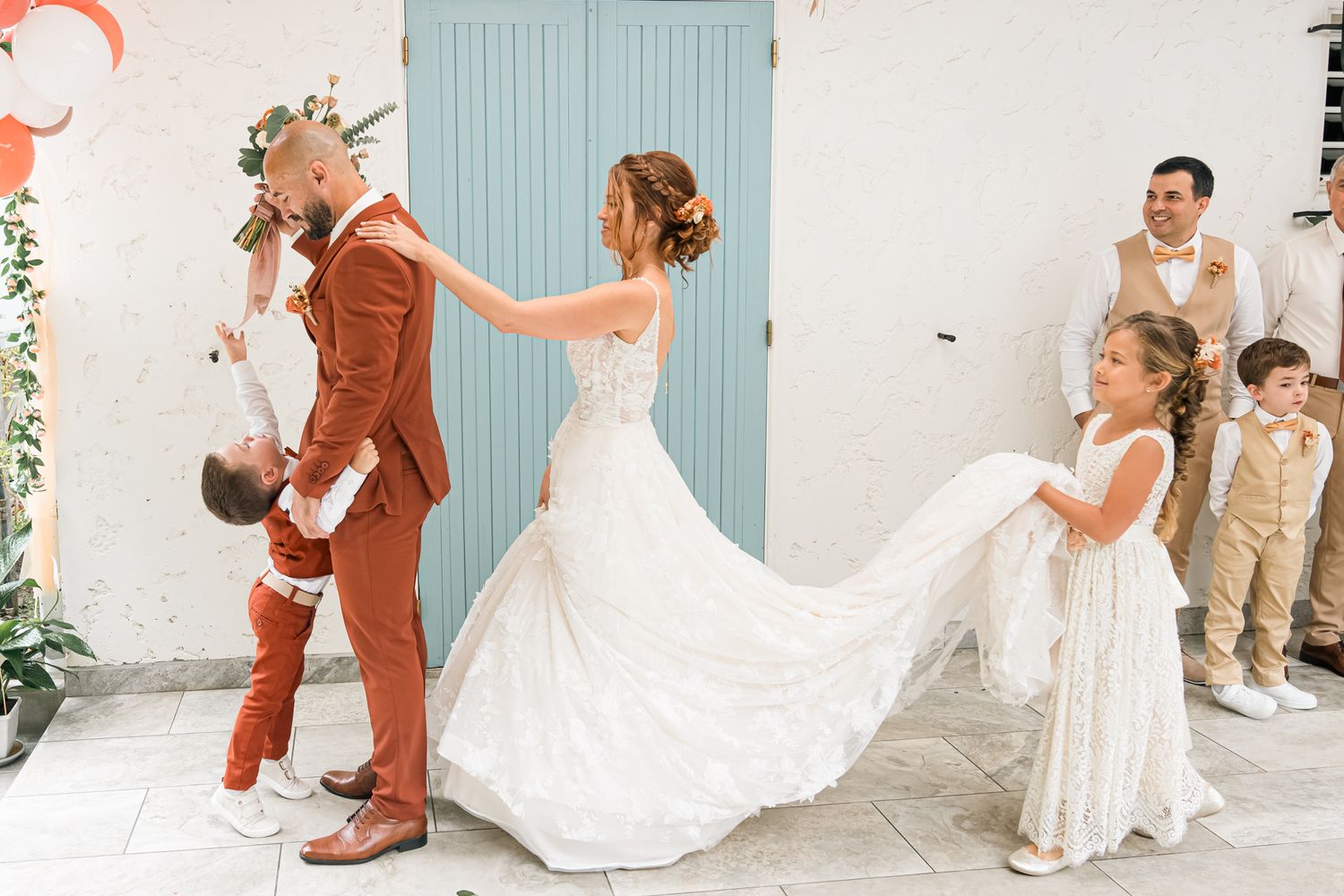 Wedding party having a playful moment during photo session with elegant bride in flowing white gown.
