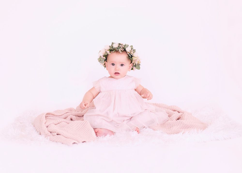 Ethereal portrait with baby wearing floral crown and pink dress.