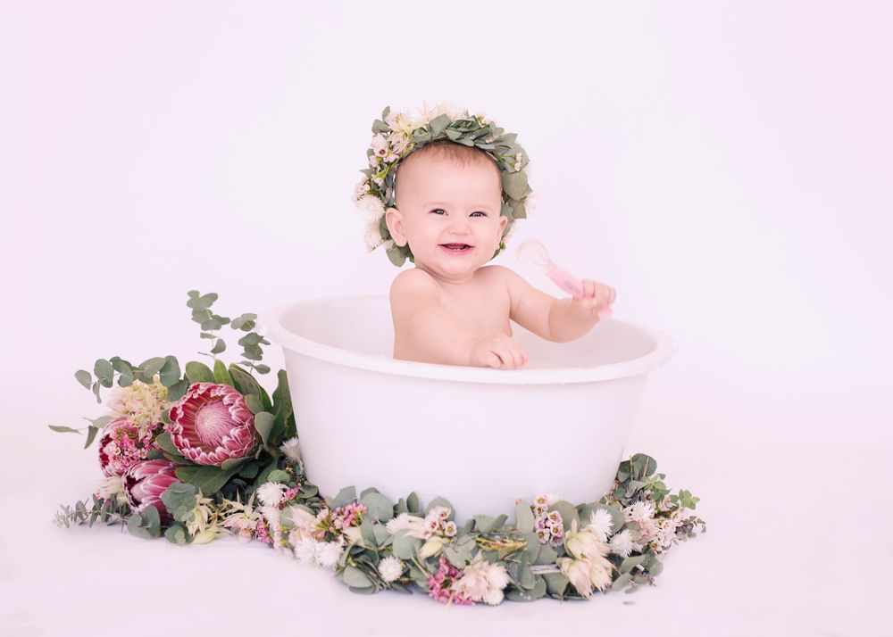 Joyful bath time portrait with floral decorations and white tub.