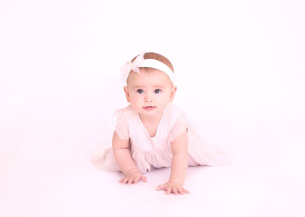 Minimalist portrait on white background with soft pink tones and delicate headband accent.