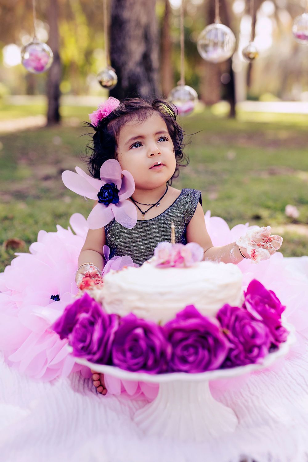 Enchanted garden theme with pink tulle dress, purple roses, and hanging glass decorations.