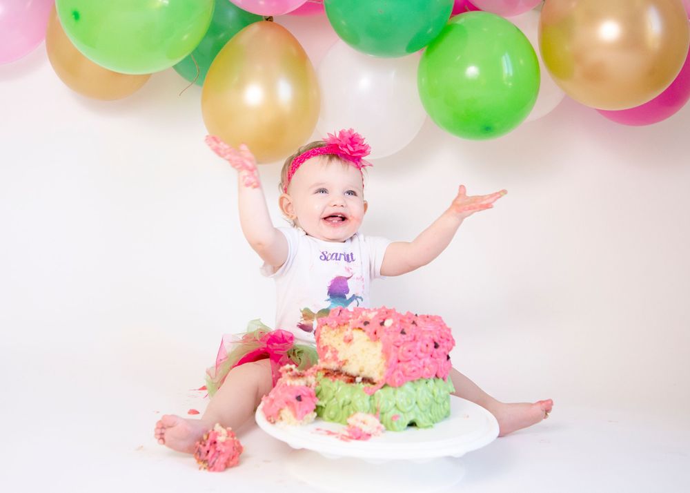Whimsical watermelon-themed photo with green and gold balloons and pink accessories.