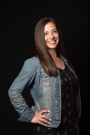 Business woman, with jean jacket, posing for a portrait with a smile.