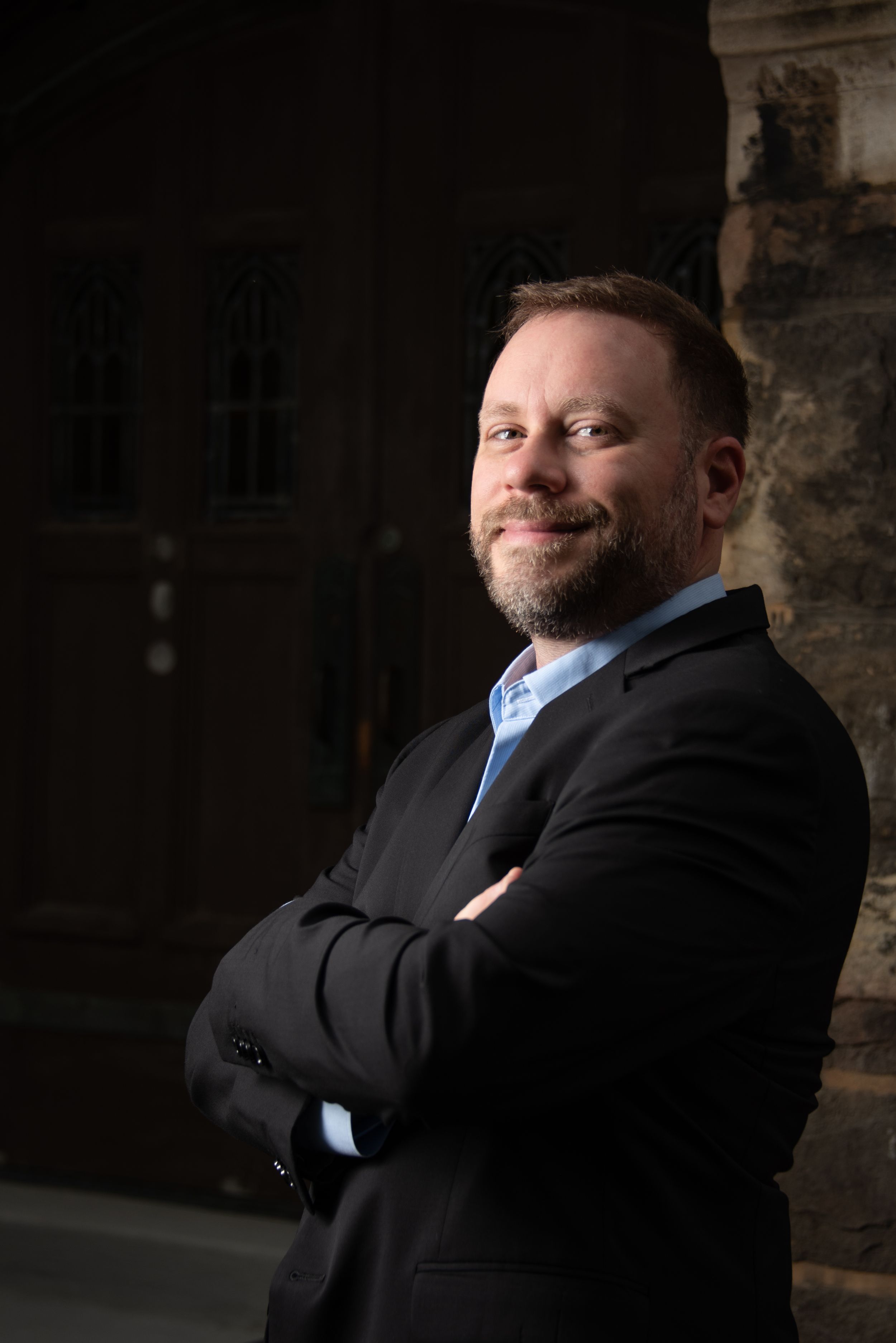 Business man, with a studio style portrait, smiling with a high contrast shot.