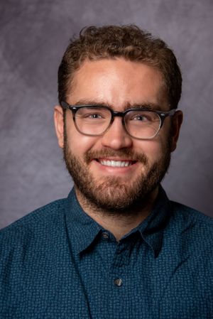 headshot of man smiling with blue shirt