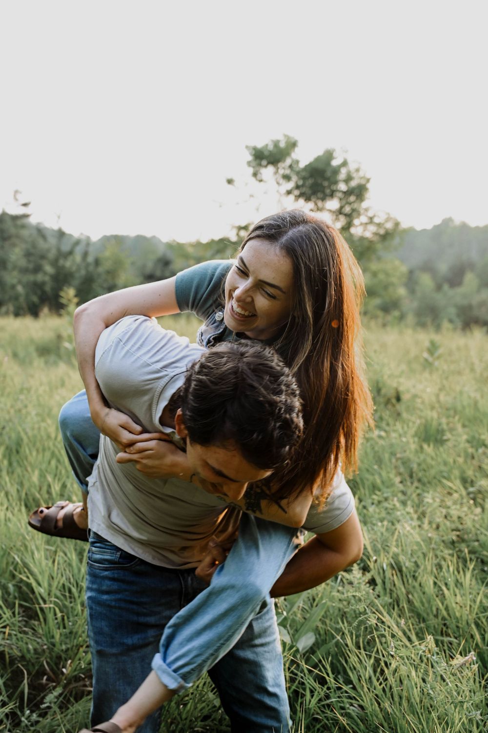 Playful couple sharing a tender moment together in a sunlit meadow at golden hour.