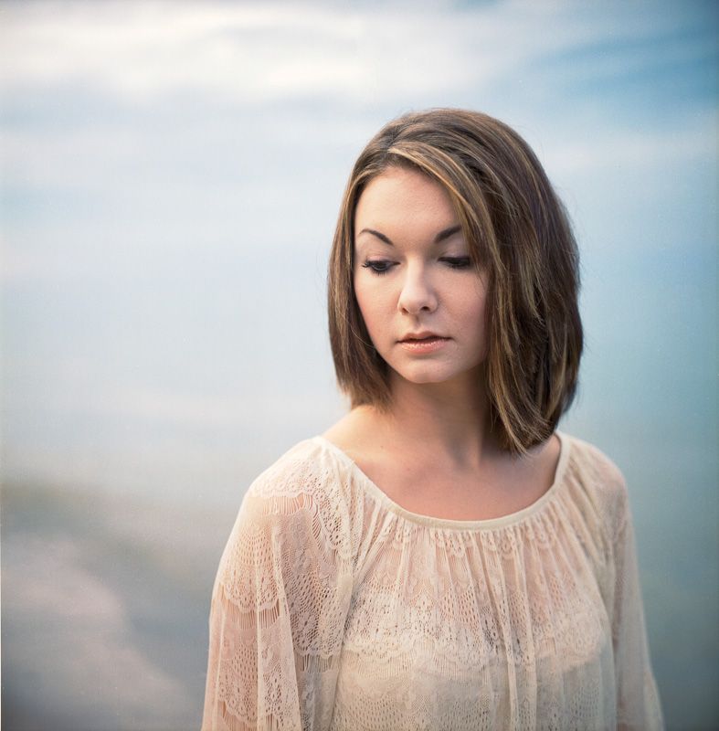 Portrait in soft natural light against cloudy sky.