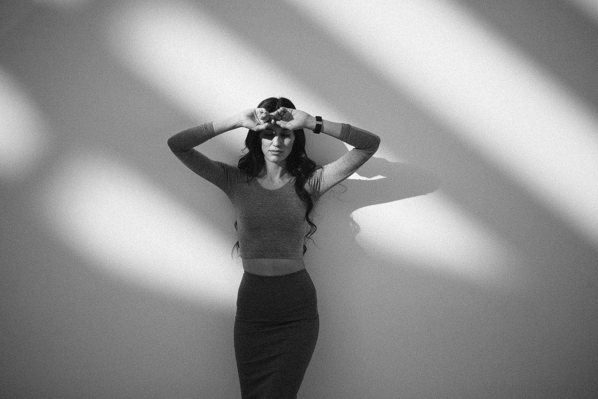 Dramatic black and white studio portrait with diagonal lighting and shadow patterns.