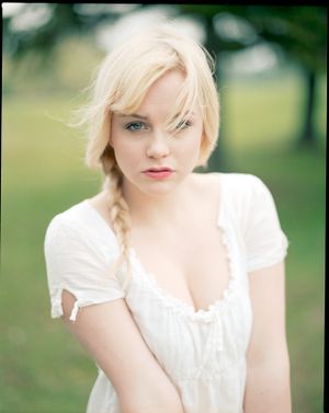 Portrait in white dress against soft green bokeh background showing ethereal summer style.
