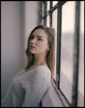 Elegant indoor portrait by window in soft knit sweater with natural lighting.