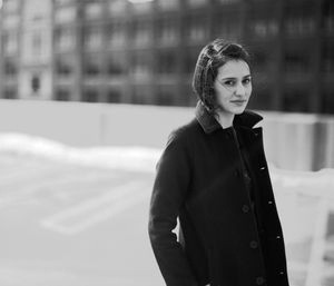 Classic black and white winter portrait in dark coat against snowy background.