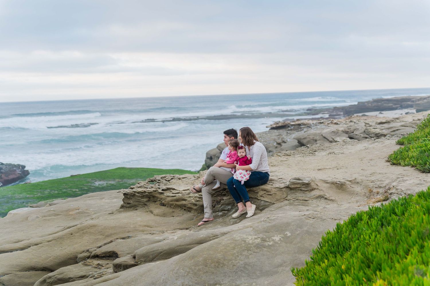 Family enjoying quality time together on rugged coastal rocks by the ocean.