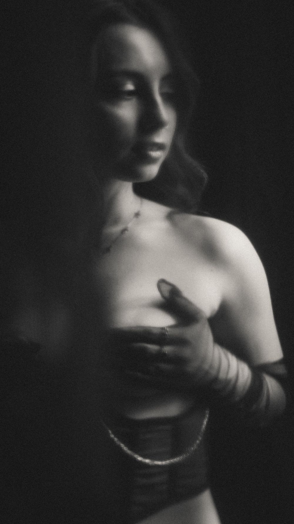 Artistic black and white portrait with dramatic lighting and shadows.