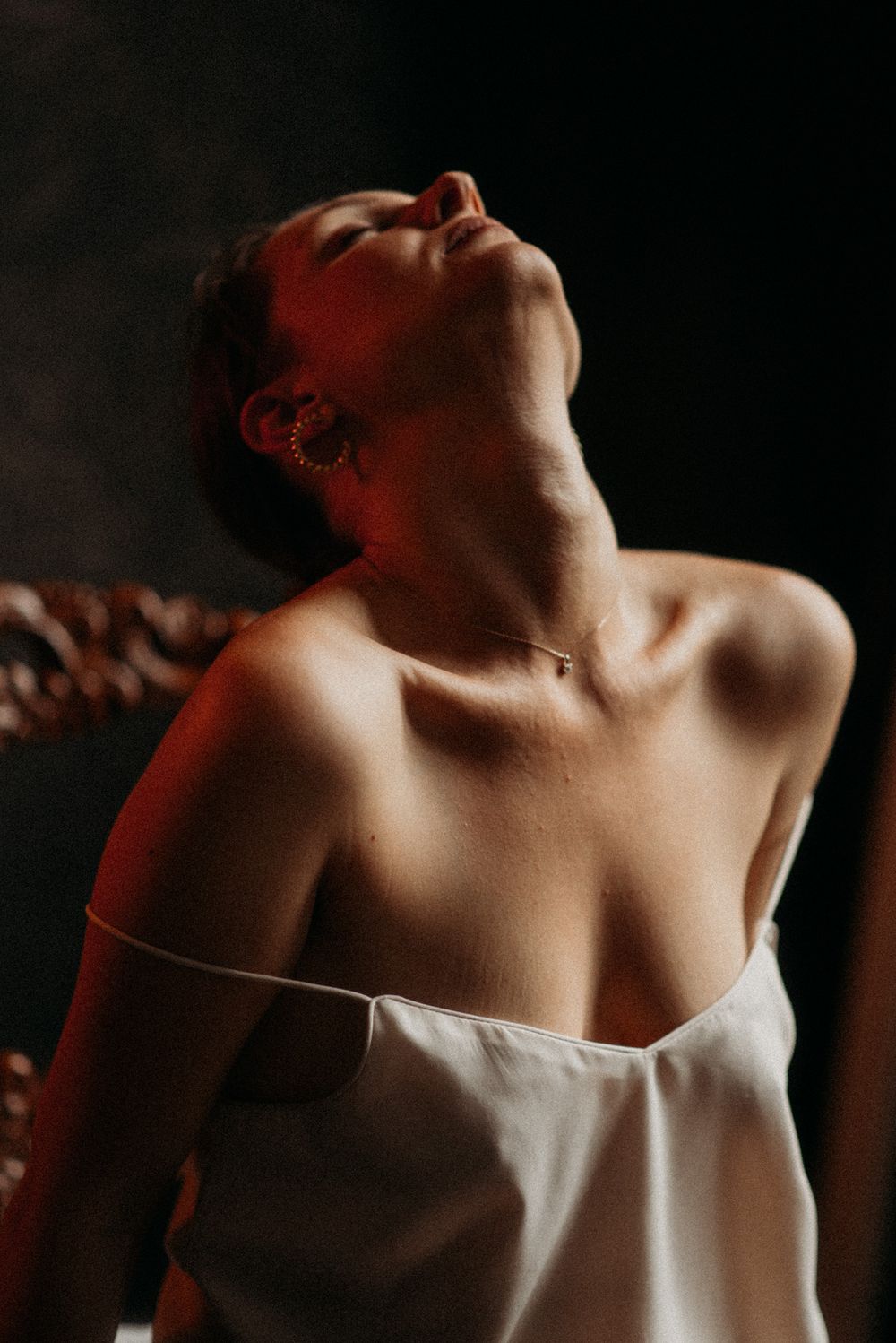Dramatic close-up portrait showing bare shoulders in warm lighting.
