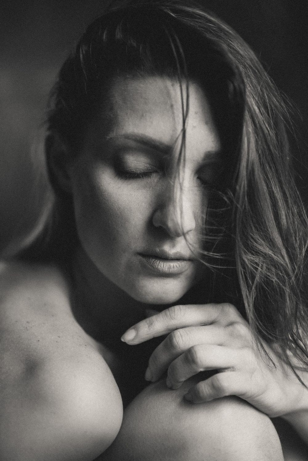 Intimate black and white portrait with gentle shadows and natural light.