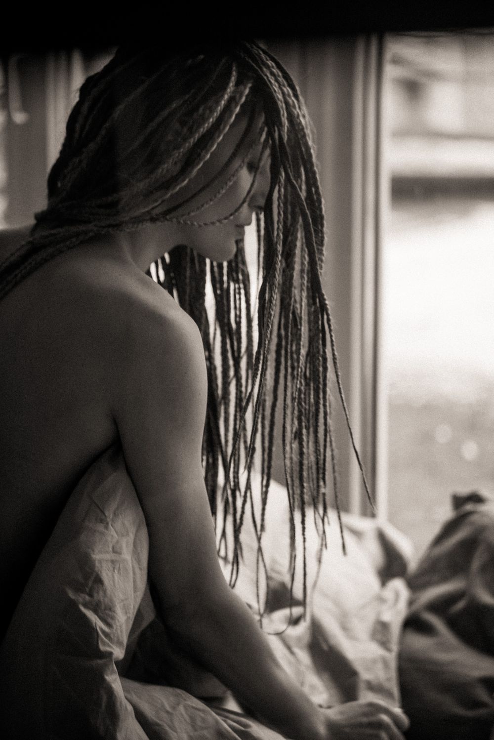 Artistic black and white portrait showing hair and shoulders in natural window light.