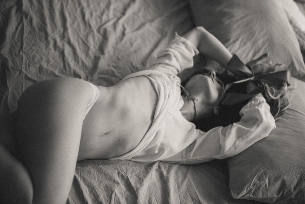 Minimalist monochrome photograph of rumpled bedsheets in morning light.