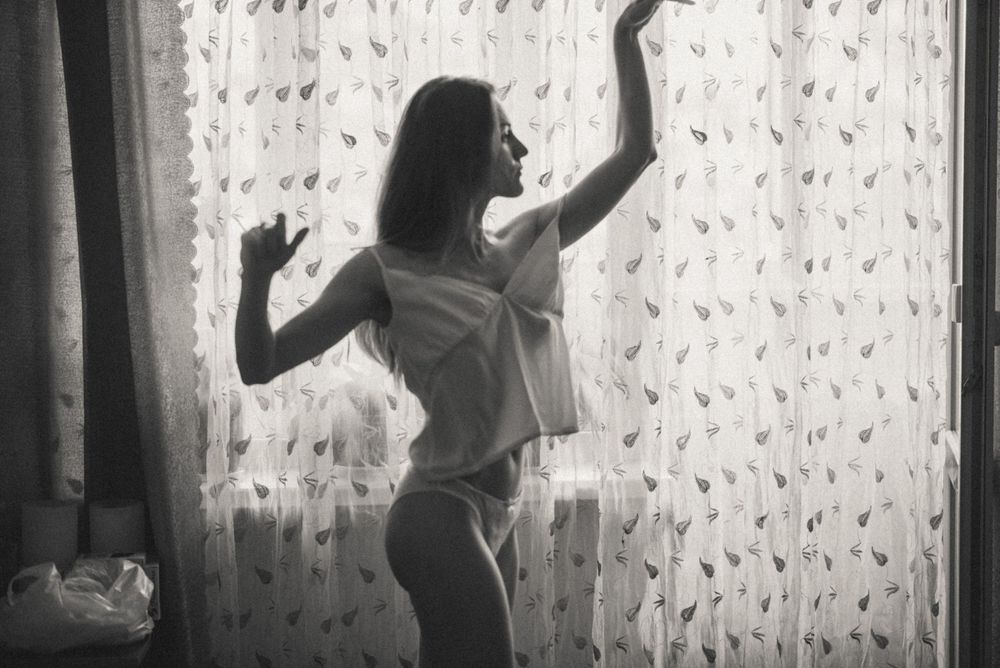 Silhouette dancing against sheer curtains in natural window light.