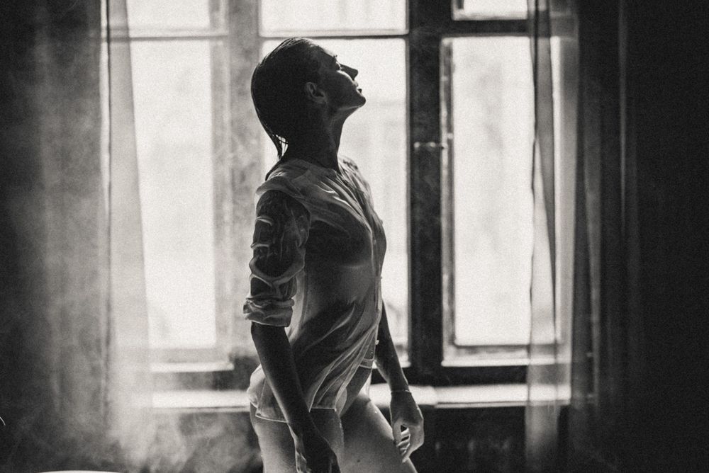 Dramatic black and white portrait with streaming window light and architectural elements.