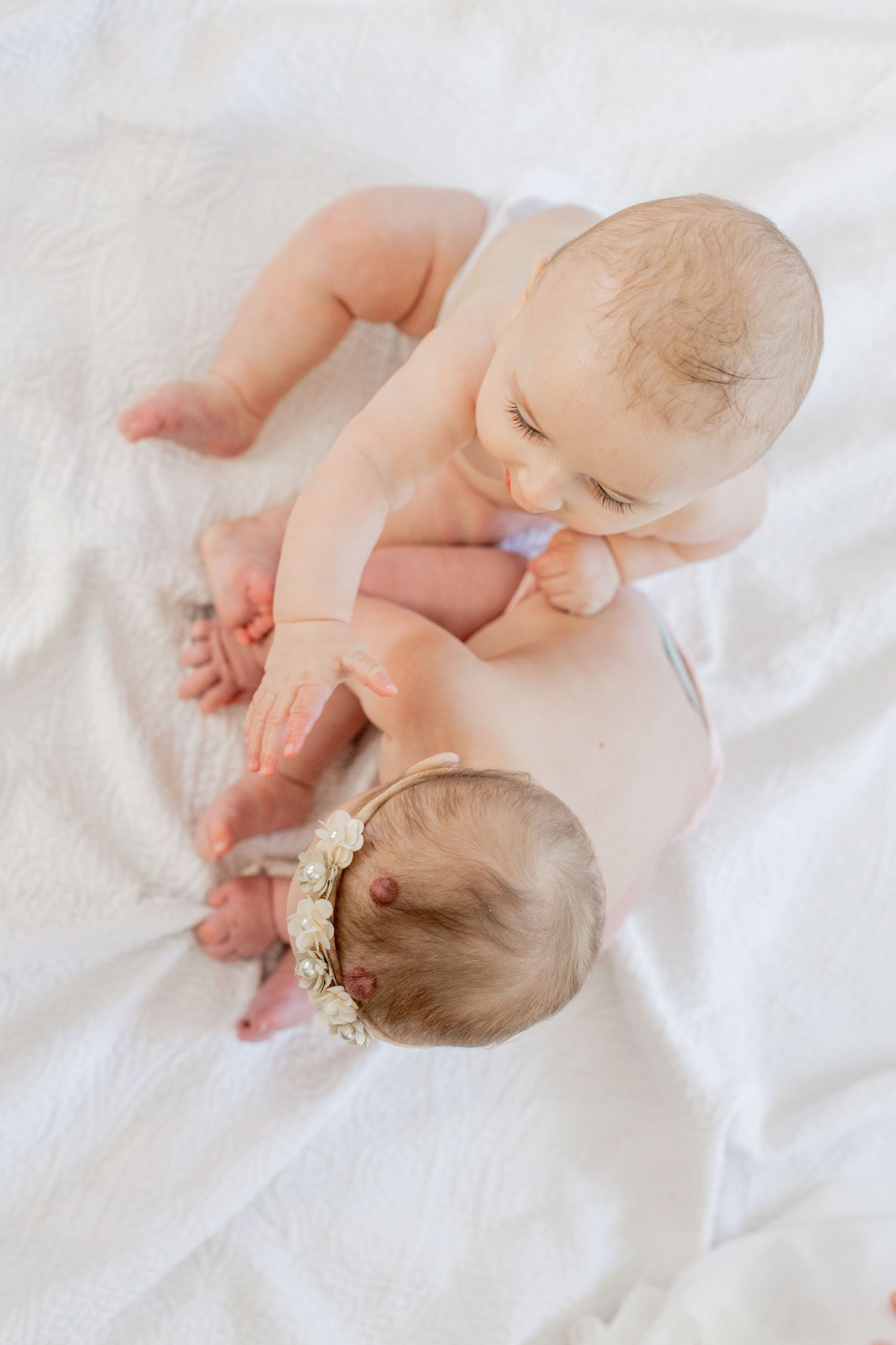 Two babies lying together on white blanket in their home in Springfield, Missouri