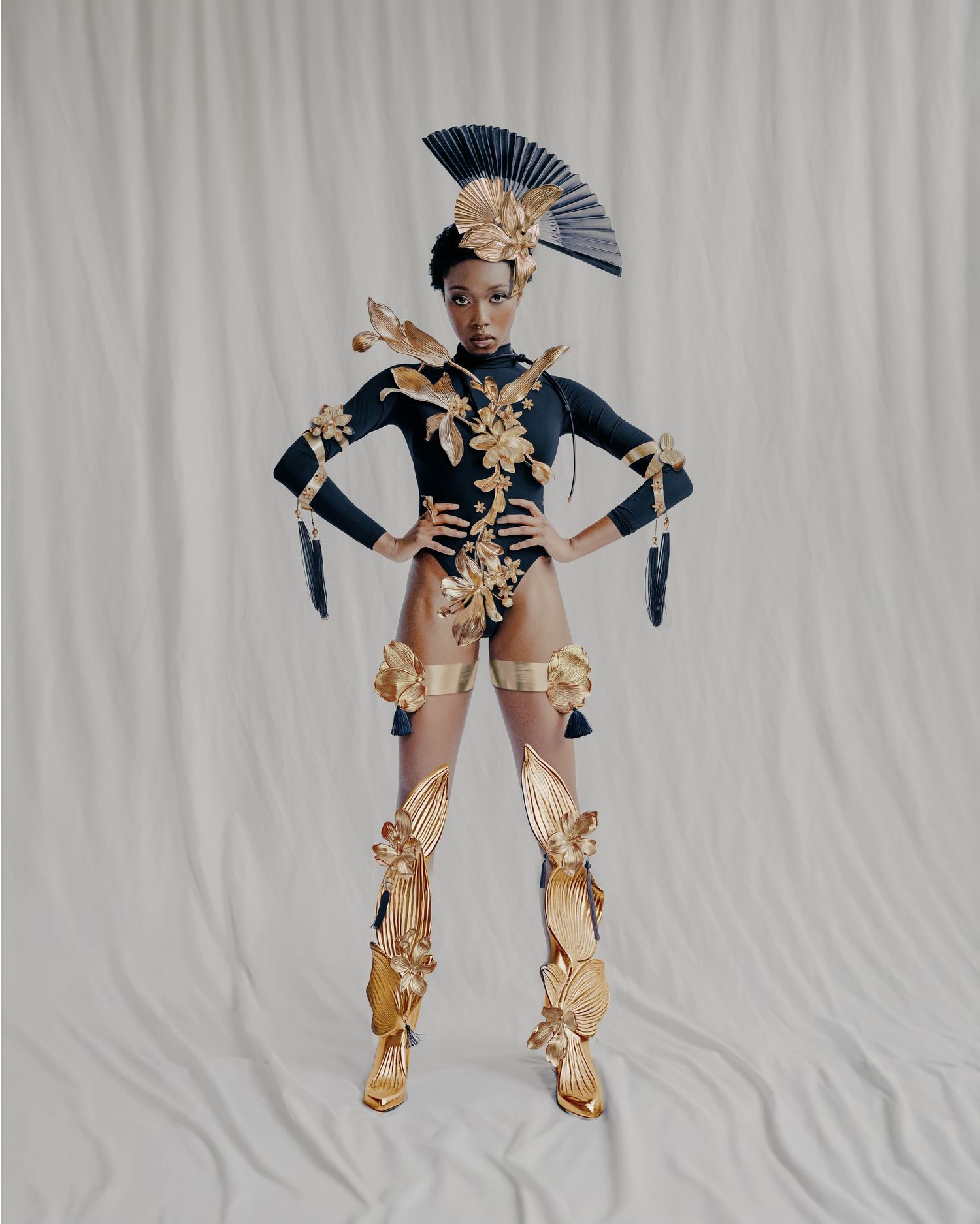 Avant-garde fashion look featuring navy and gold costume with dramatic fan headpiece.