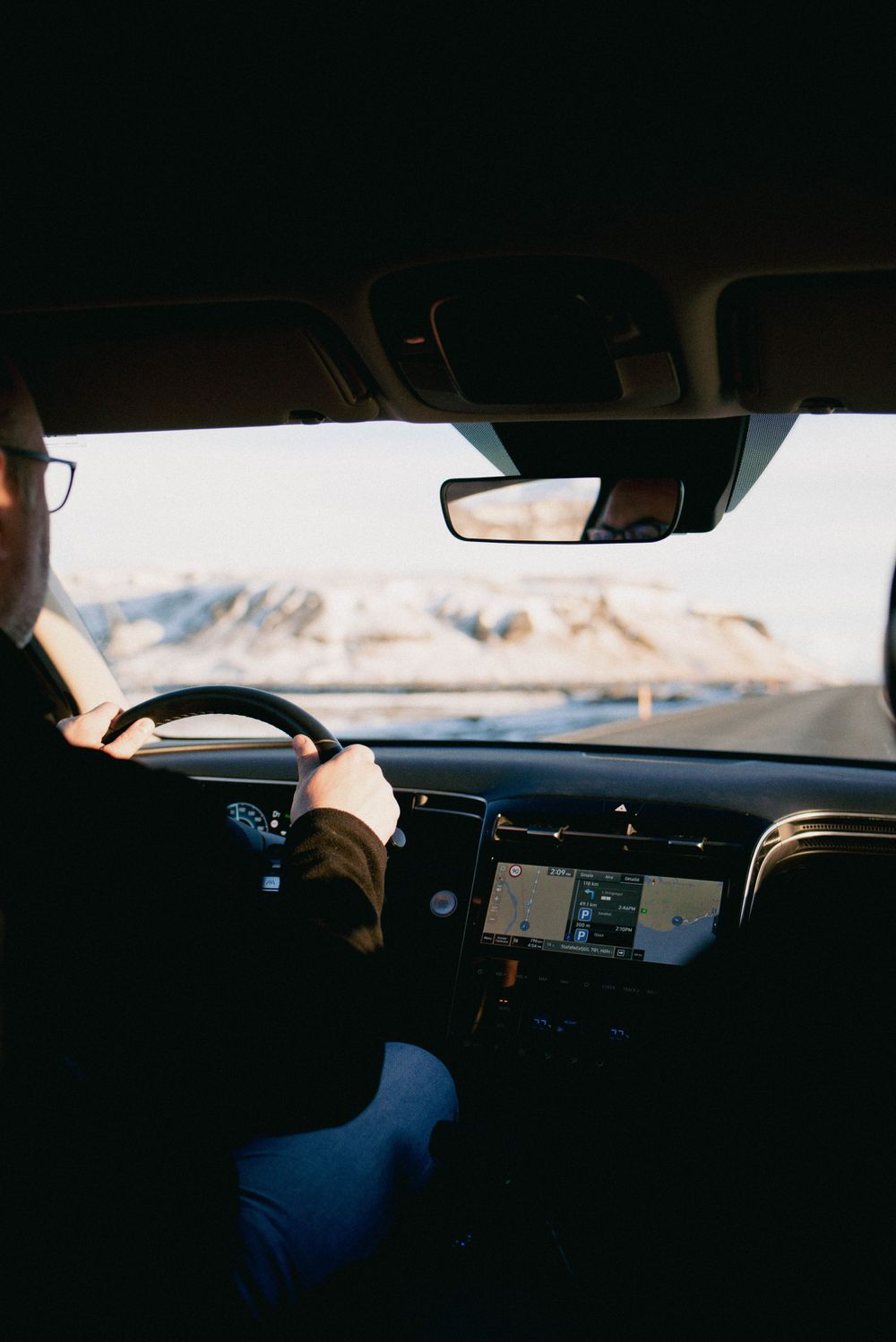 Le conducteur navigue sur une route enneigée avec la navigation GPS à l'intérieur de la voiture.