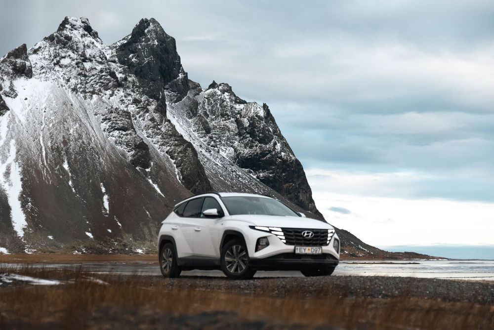 Le SUV multisegment Hyundai blanc garé devant des sommets de montagnes spectaculaires enneigés en Islande.