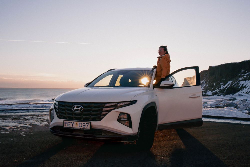 SUV Hyundai blanc garé le long de la route côtière au coucher du soleil.