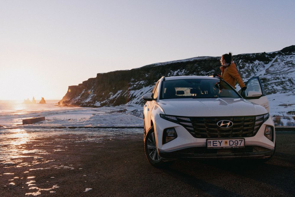 Véhicule Hyundai garé sur la route côtière avec un coucher de soleil spectaculaire et des falaises en arrière-plan.