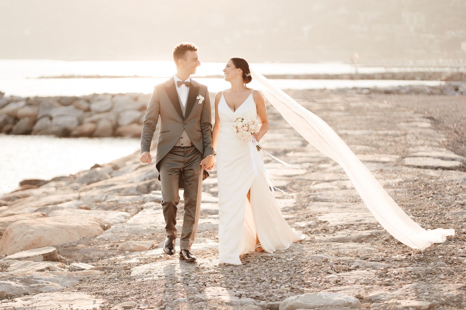 Matrimonio in Liguria: Gli sposi camminano al tramonto in spiaggia ad Alassio, in provincia di Savona.