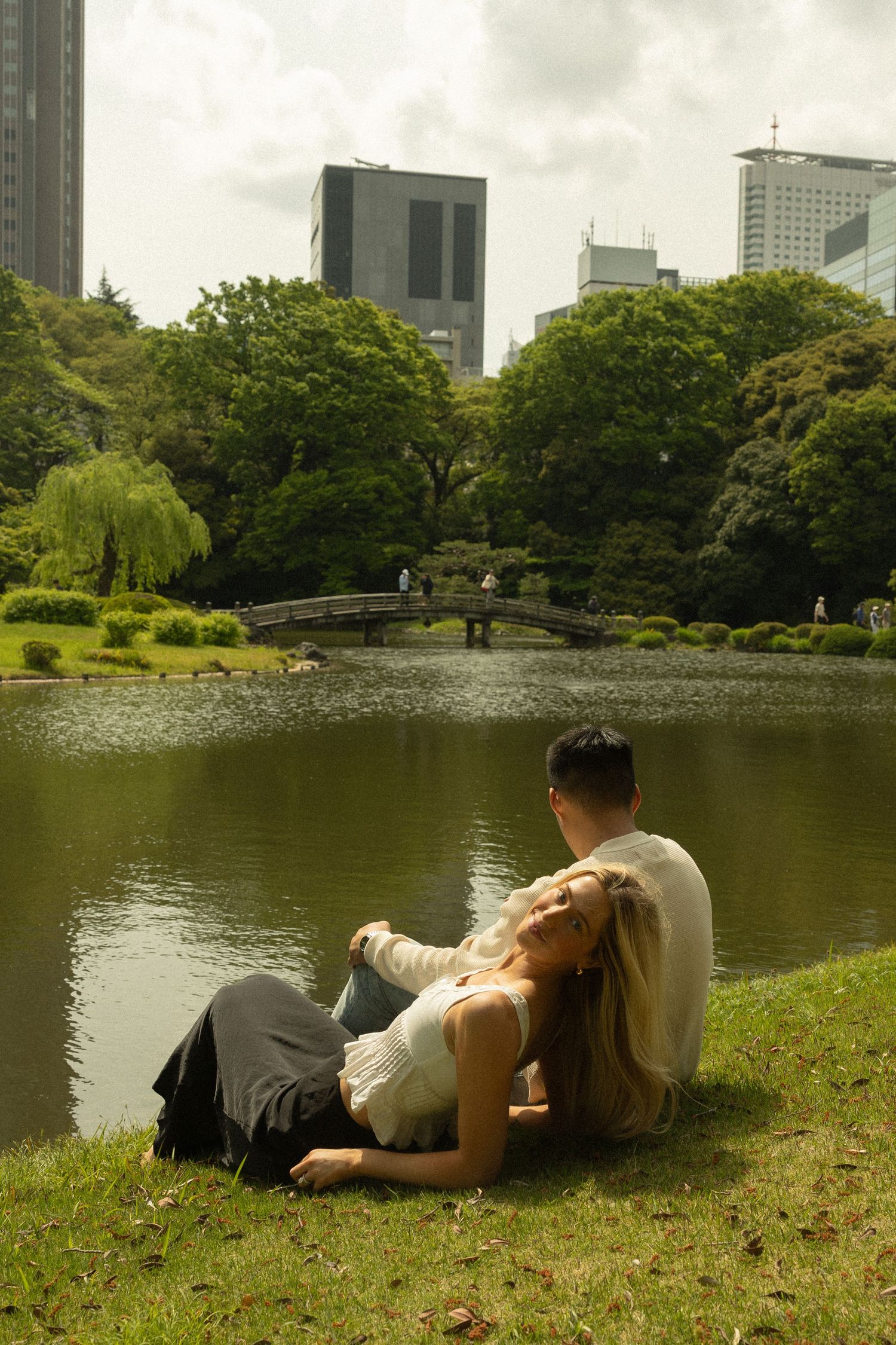 A couple embraces under blooming pink cherry blossoms in a romantic spring garden setting.