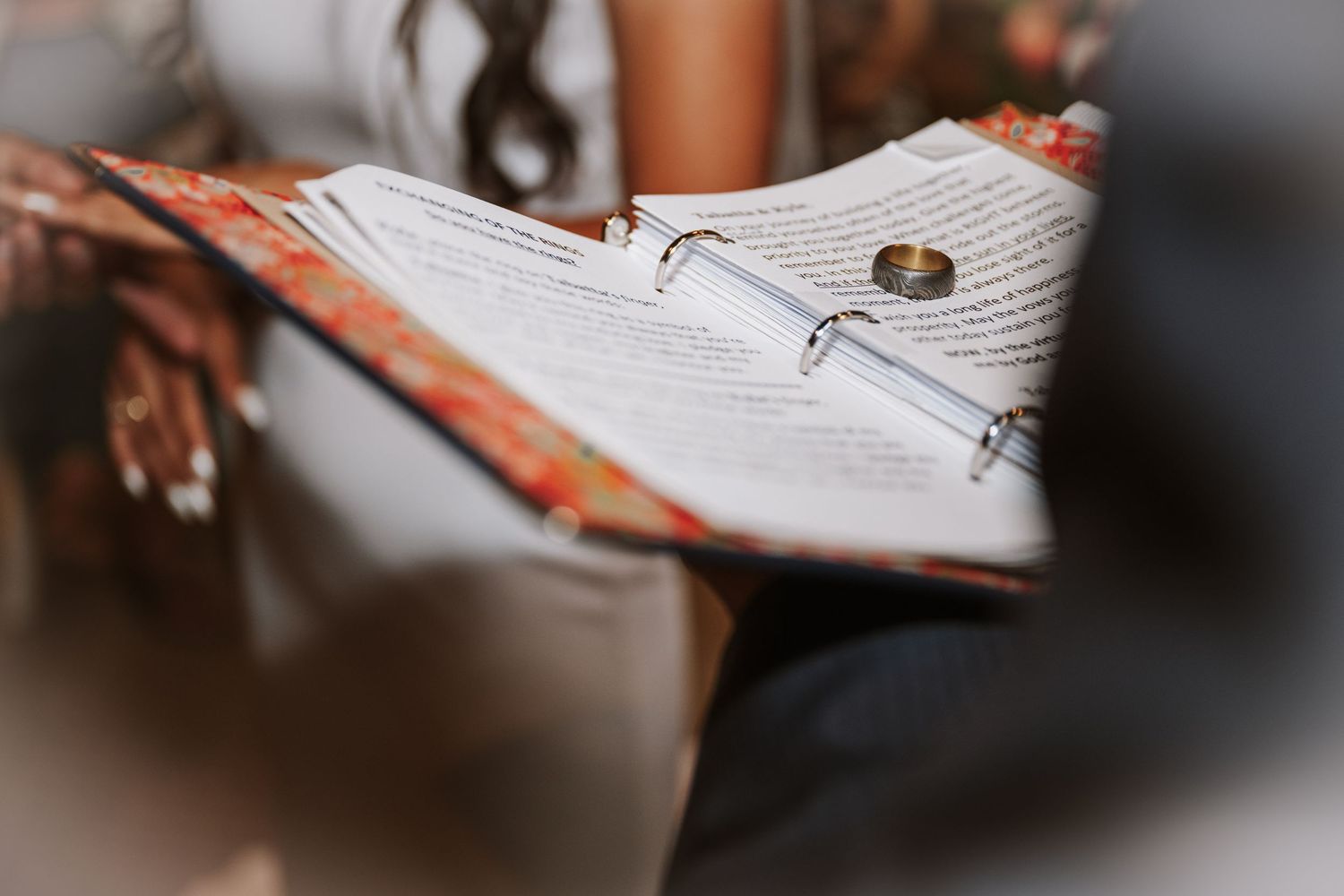 An open white lined notebook page with a silver pen lying on it seen in a blurred close-up view.