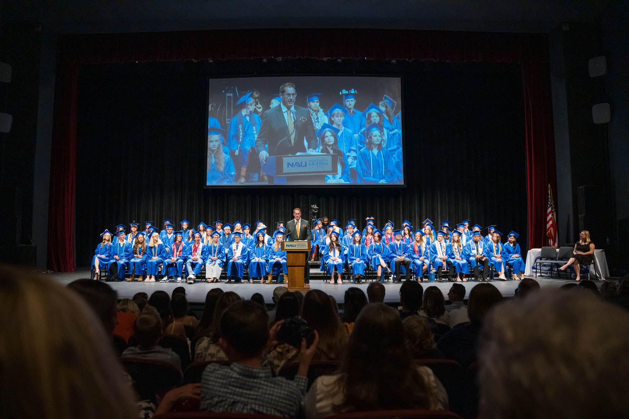 NPA Superintendent David Lykins addresses graduates at the podium with students who delivered welcome portions in Spanish and Diné.