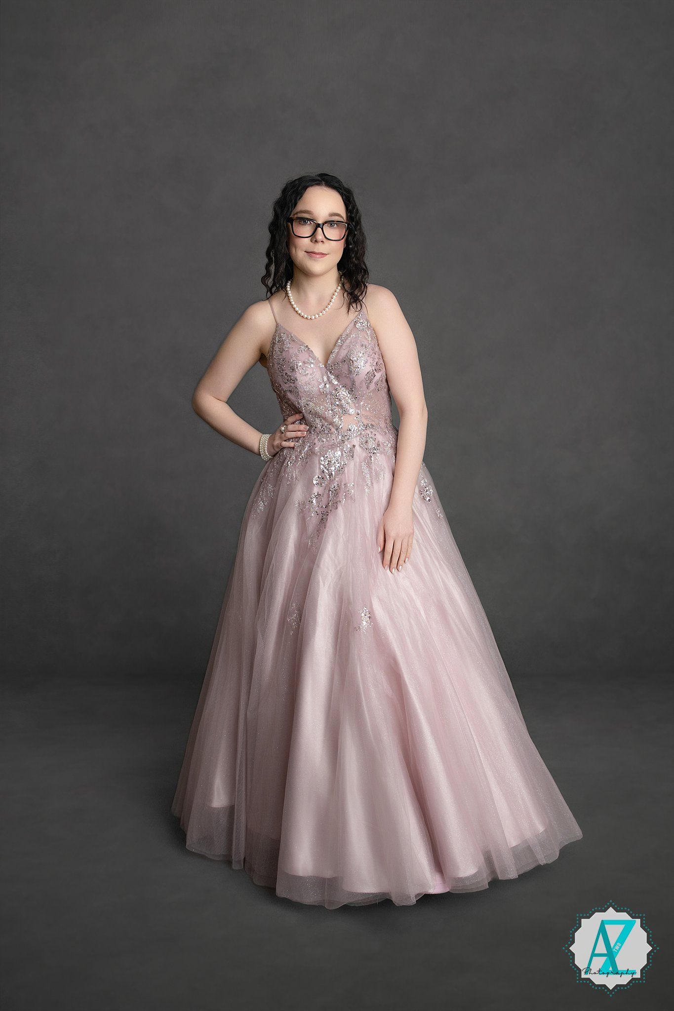 Elegant dusty pink ball gown with lace appliques and tulle skirt photographed against dark grey backdrop.