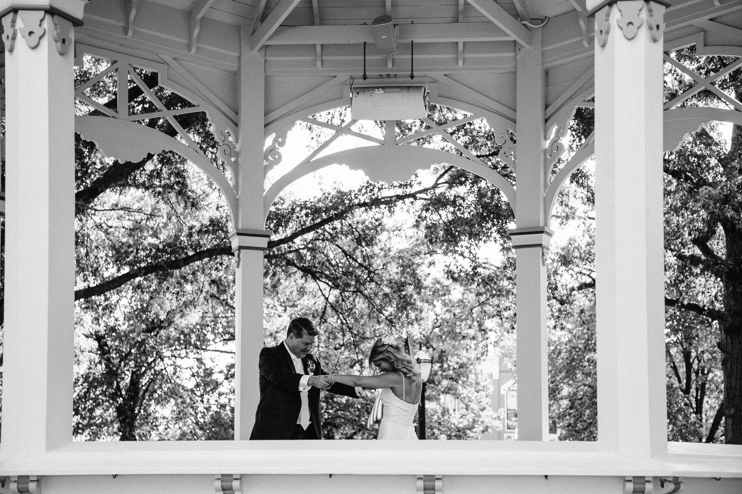 Candid bride and groom first look under a gazebo in Medina town square.