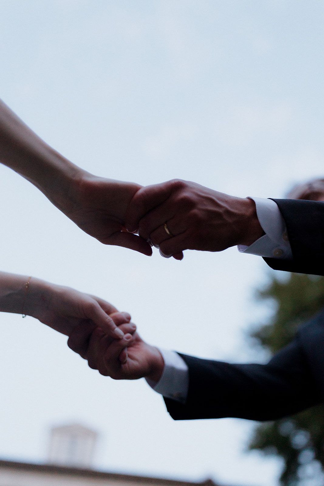 Close up of hands touching during a wedding ceremony against a light background.