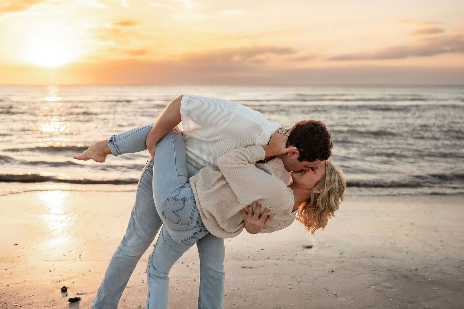 Couple dancing and embracing on beach at sunset.