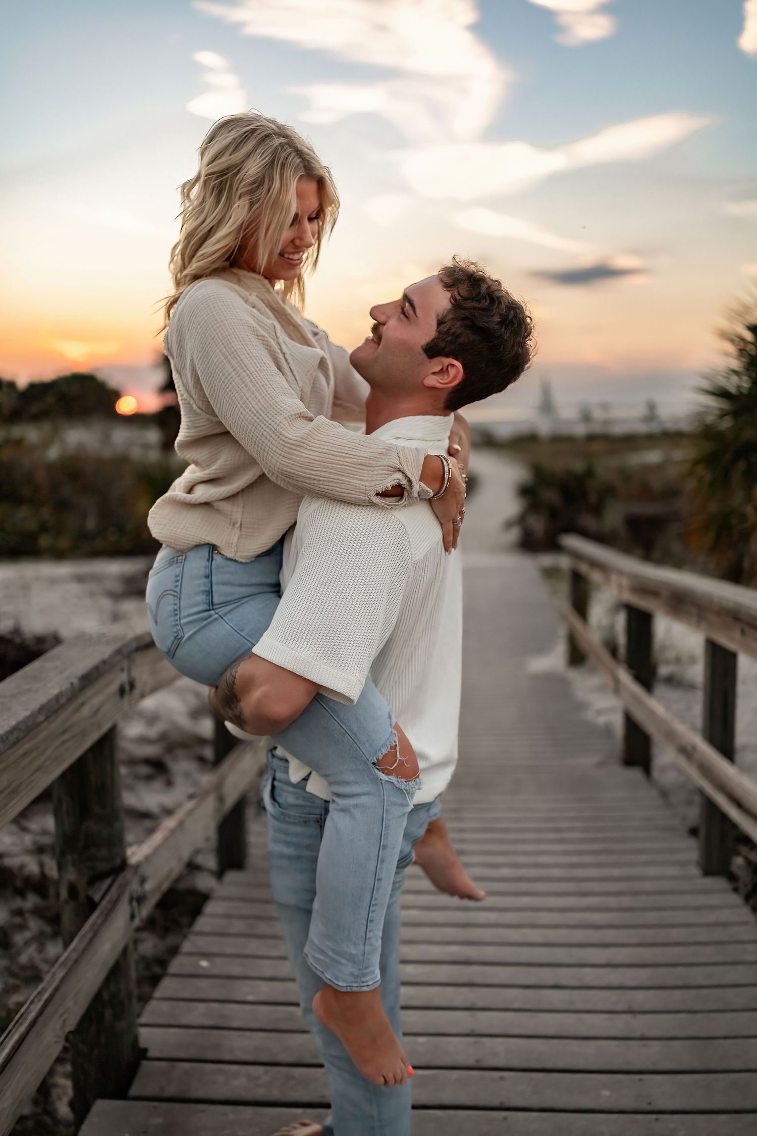 Romantic seaside boardwalk photos with couple in matching light colors.