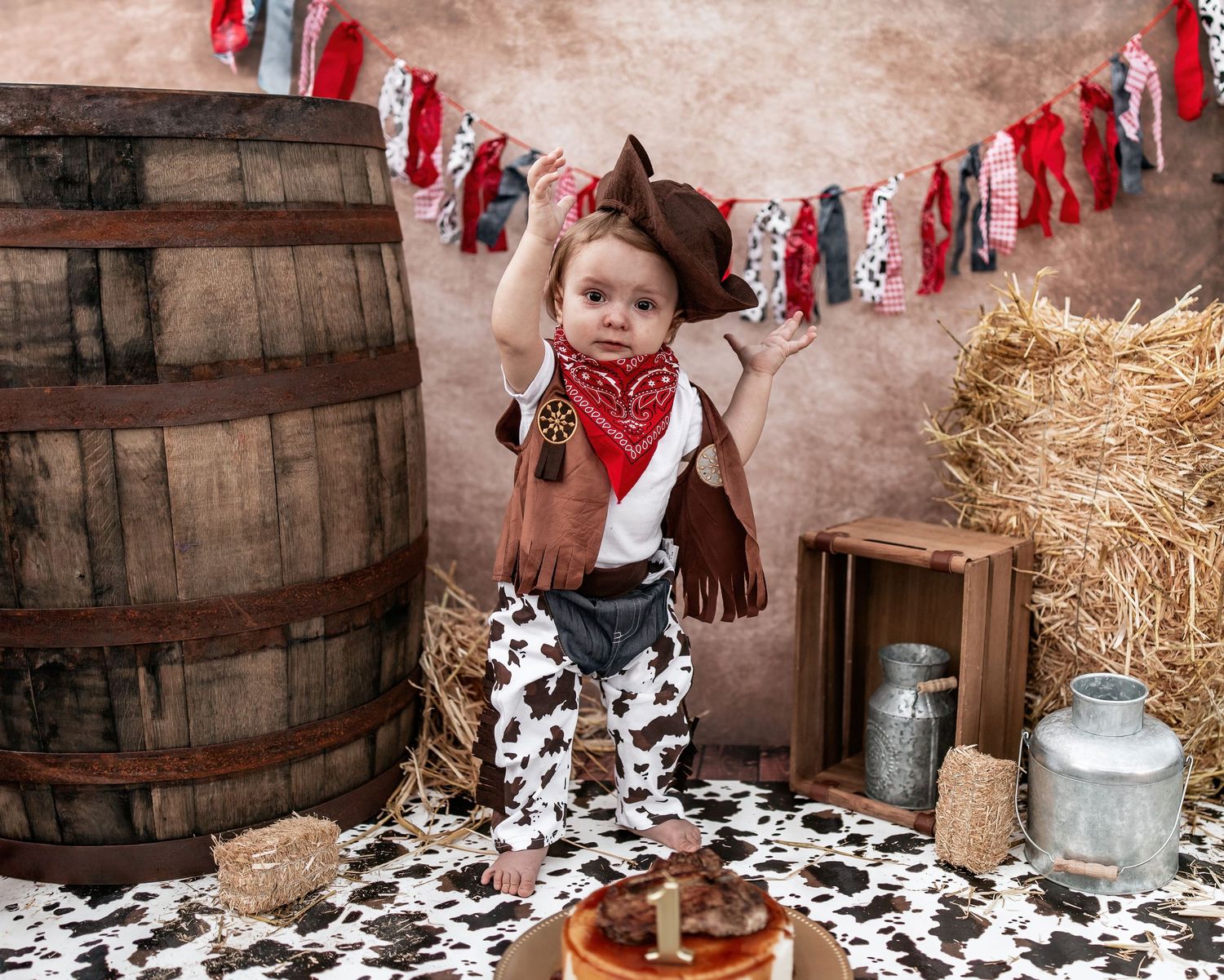 Western themed first birthday setup with cow print, red bandanas and hay bales.
