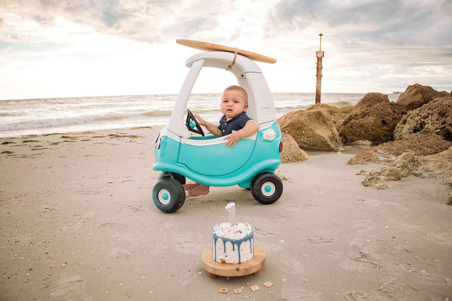 Beach scene with toy car and props set up for professional photoshoot at sunset.