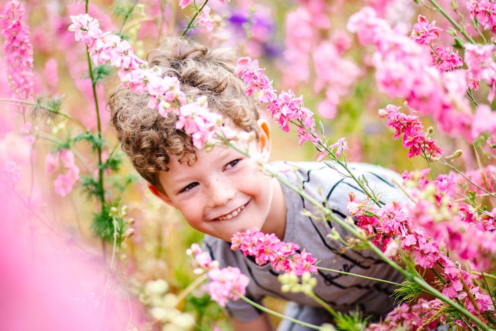 A joyful spring moment captured amid blooming pink cherry blossoms and purple flowers in soft natural lighting.