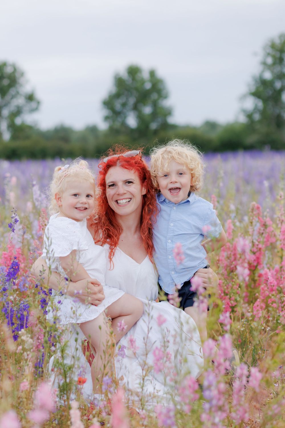 A joyful outdoor portrait in a vibrant wildflower field filled with purple and pink blooms on a summer day.