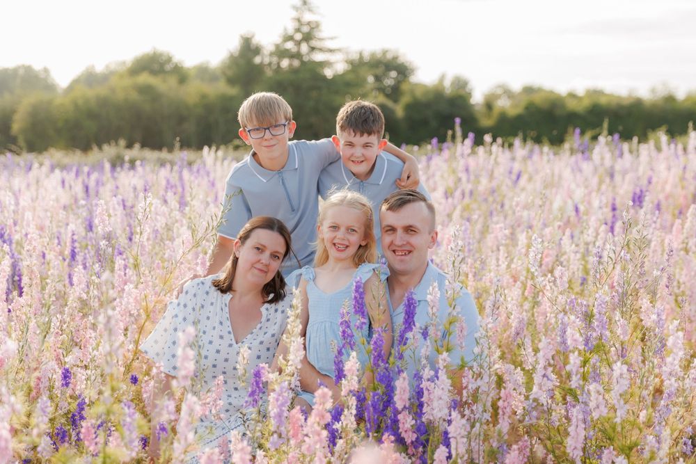 A group poses together in a beautiful field of purple wildflowers during golden hour.
