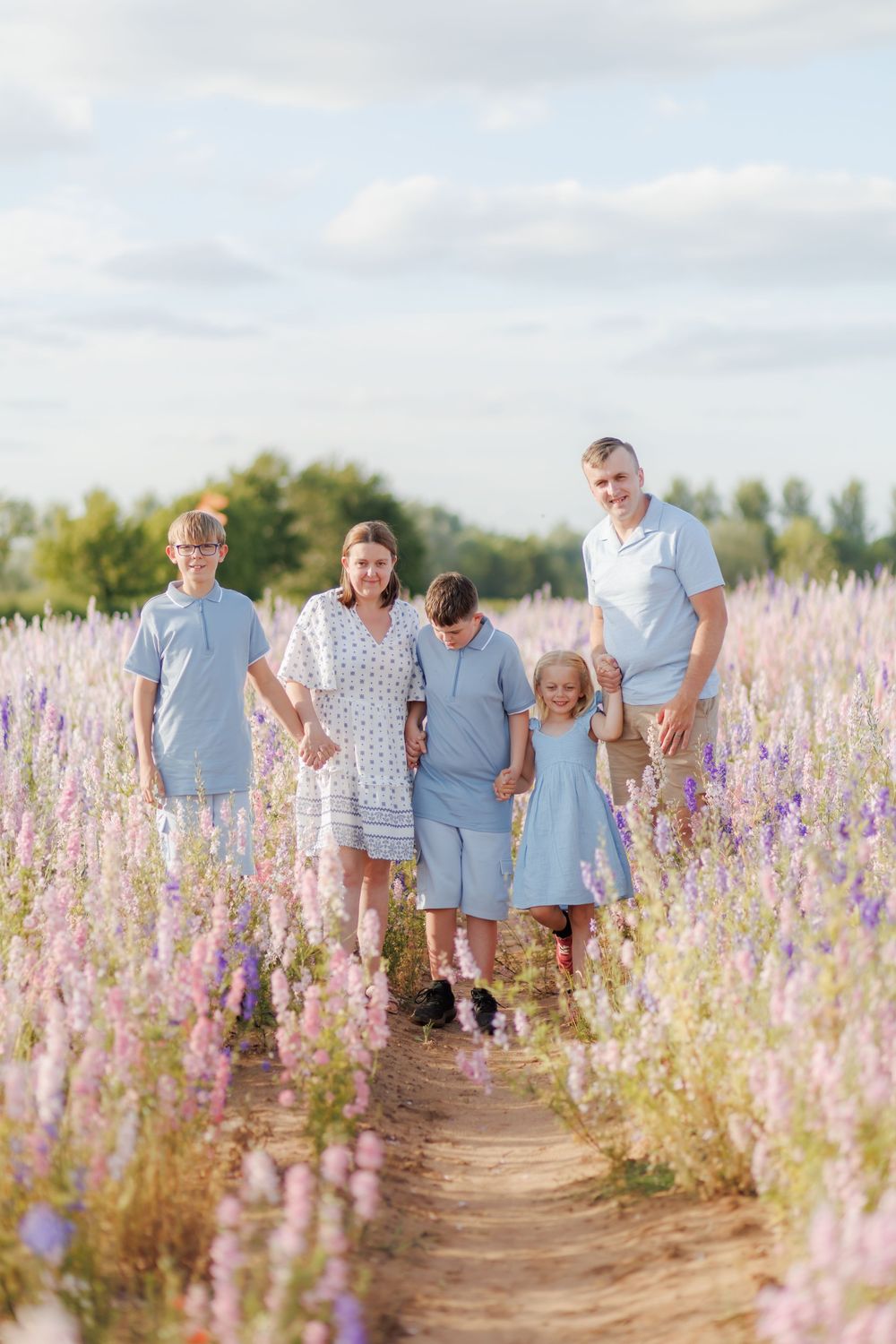 A group of people walk through a beautiful field of blooming purple and pink wildflowers on a sunny summer day.