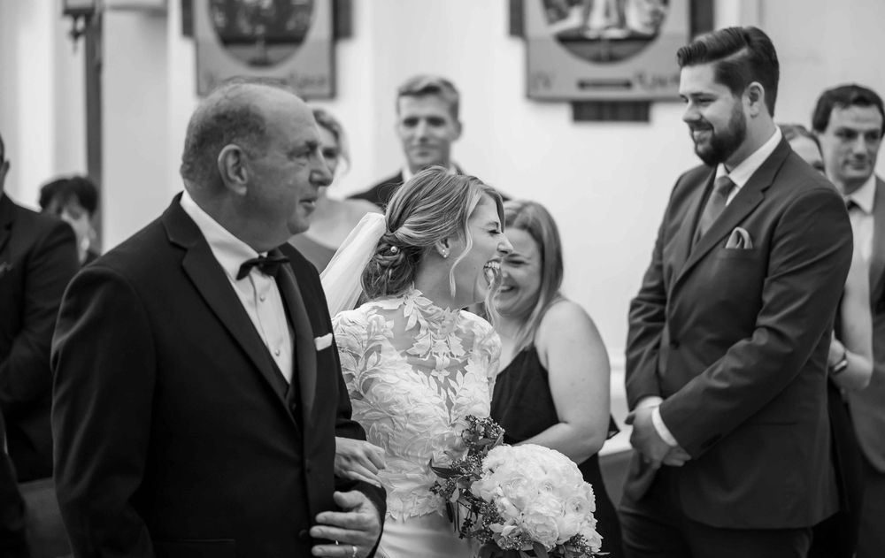 A joyful black and white photo capturing a candid moment during a wedding ceremony with guests showing genuine emotion.